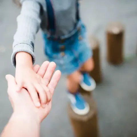 Un adulte qui tend sa main vers un enfant